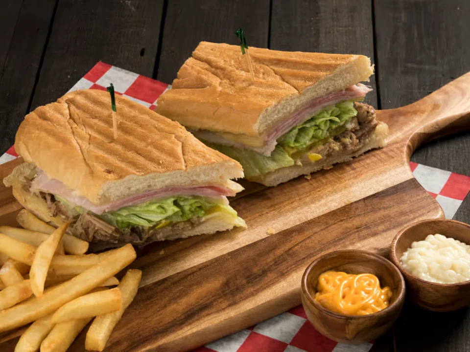 Real Cubano - Our authentic Cuban sandwich loaded with roasted pork, ham, Swiss cheese, pickles, and mustard on pressed Cuban bread.
